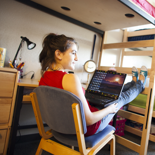 Smiling woman in dorm room with computer