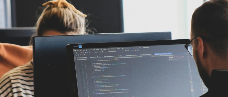 Two people across from each other working on their laptiops.